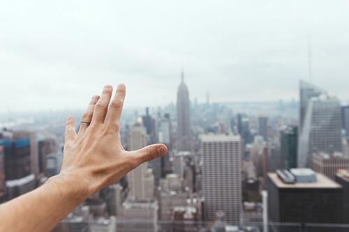 Mann mit Ring streckt Hand über die Skyline der Stadt